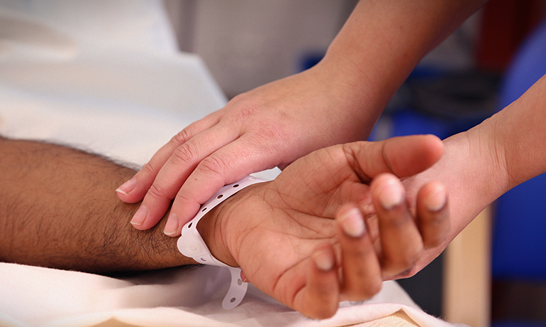 Close up of a student taking the pulse of a patient