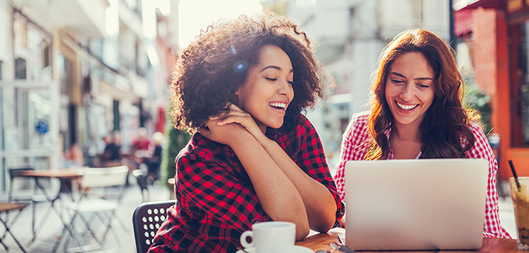 Two women looking at a computer at a cafe