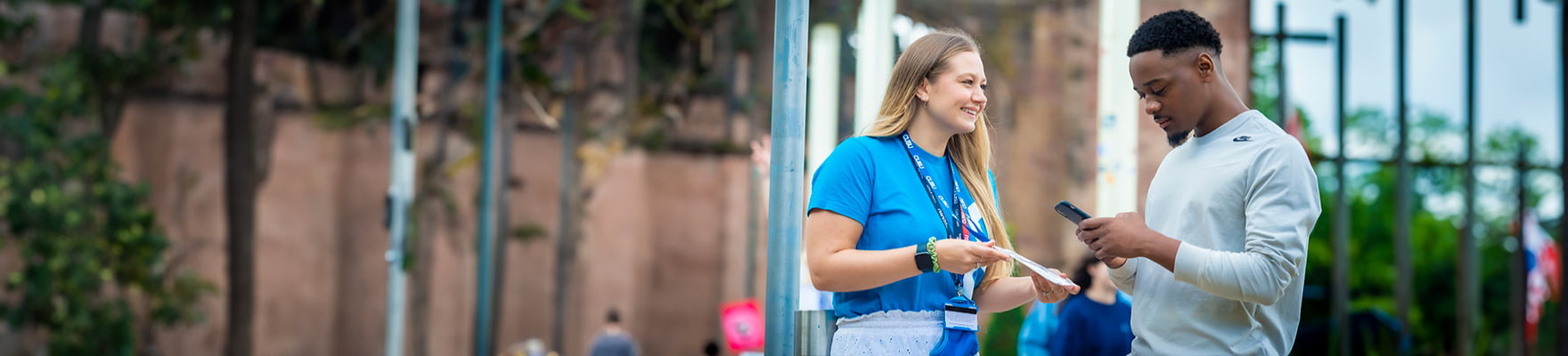 student advisor showing a student a leaflet in the catherdral grounds