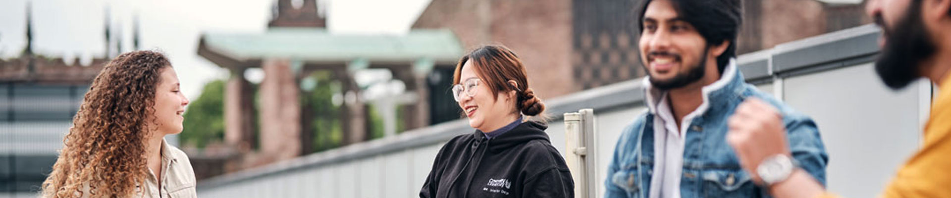 Group of students sat outside talking on a roof top terrace